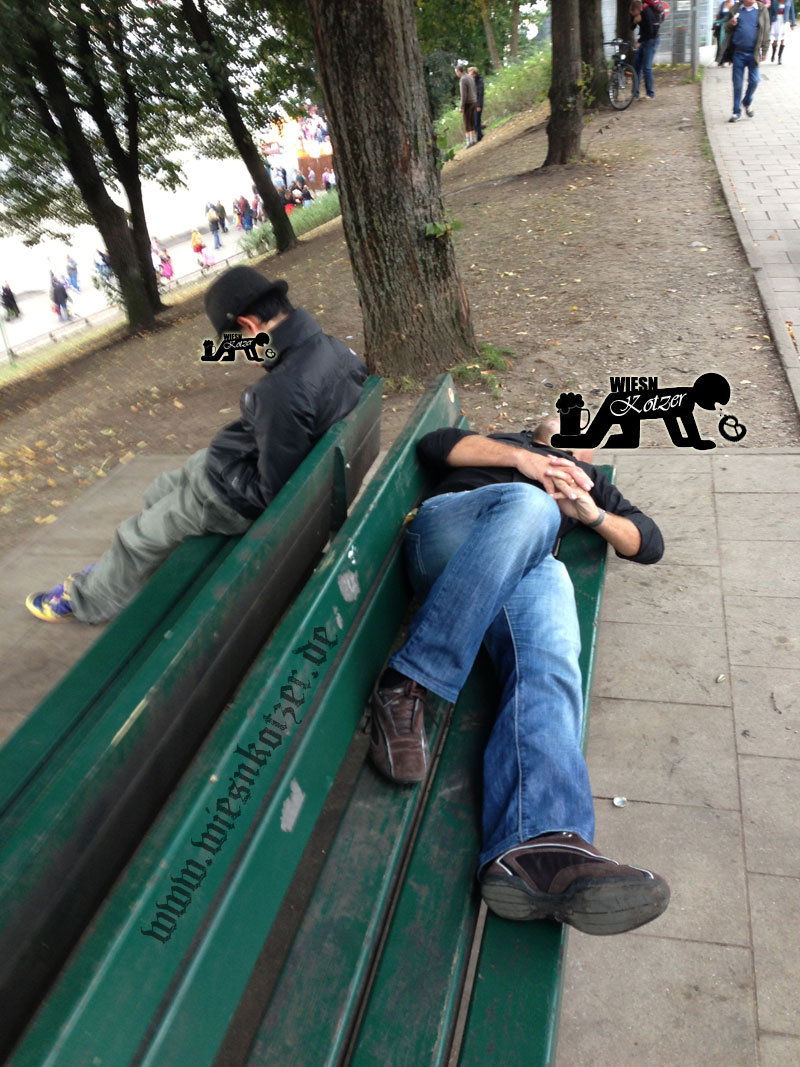 Guys sleeping on a park bench at noon